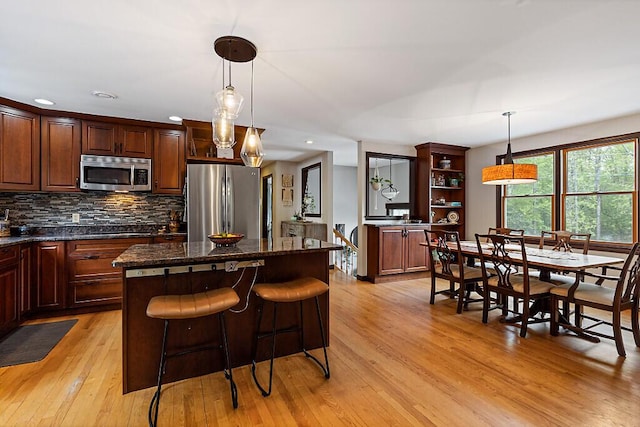 25 Parmenter Ter, China, ME 04358 - kitchen featuring appliances with stainless steel finishes, light wood-type flooring, a kitchen island, open shelves, and decorative backsplash