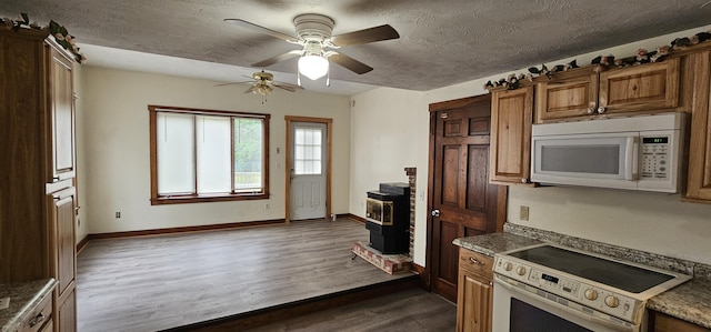 18 Pine St, Skowhegan, ME 04976 - kitchen featuring white appliances, a wood stove, a ceiling fan, brown cabinets, and dark wood-style flooring