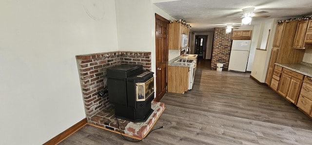 18 Pine St, Skowhegan, ME 04976 - kitchen with freestanding refrigerator, a wood stove, baseboards, and brown cabinets