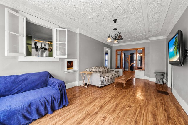43 Whales Back Rd, Sullivan, ME 04664 - living room with an ornate ceiling, wood finished floors, baseboards, a chandelier, and crown molding