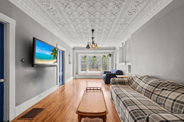43 Whales Back Rd, Sullivan, ME 04664 - living area featuring an ornate ceiling, ornamental molding, a chandelier, hardwood / wood-style floors, and baseboards