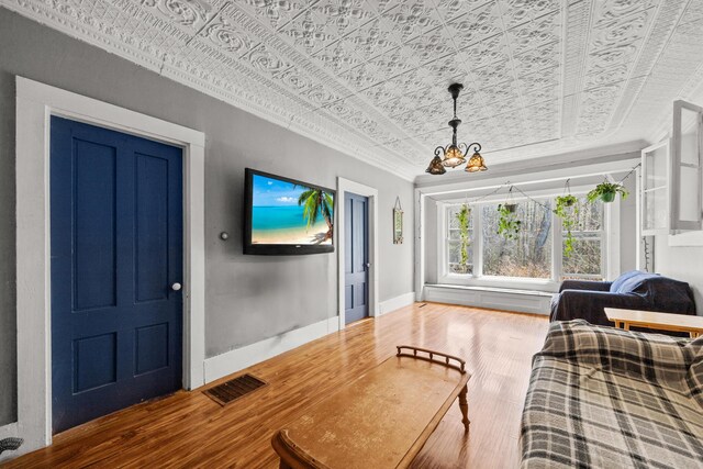 43 Whales Back Rd, Sullivan, ME 04664 - living room with an ornate ceiling, ornamental molding, a chandelier, wood finished floors, and baseboards