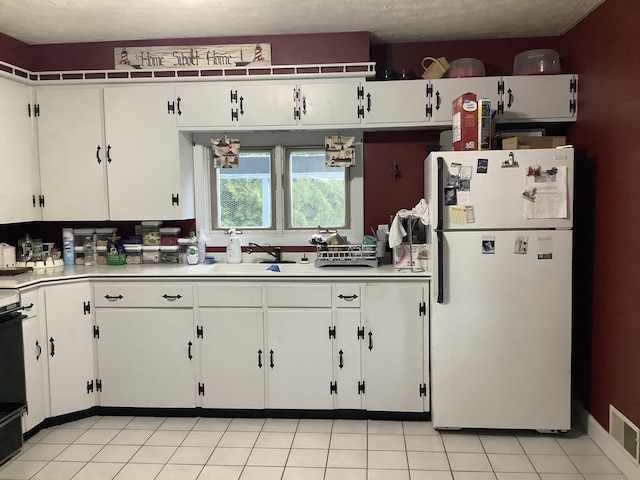 15 Blaine St, Fort Fairfield, ME 04742 - kitchen with freestanding refrigerator, light countertops, white cabinetry, and a sink