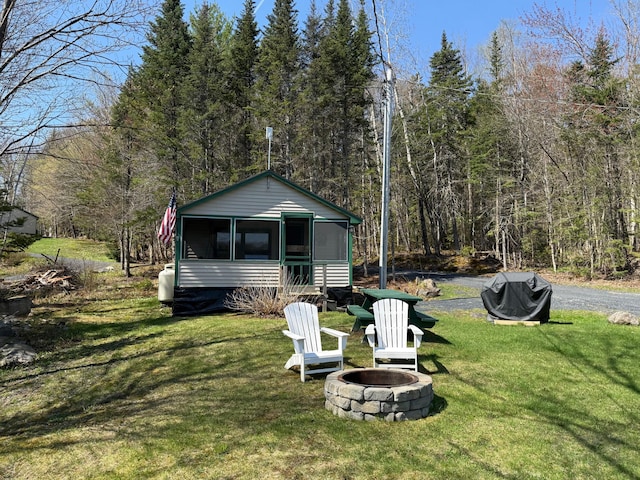 15 Wilson Pond Rd (Hedgehog), Unit Hedgehog Greenville, ME 04441 - rear view of property with an outdoor fire pit, a sunroom, a lawn, and a forest view
