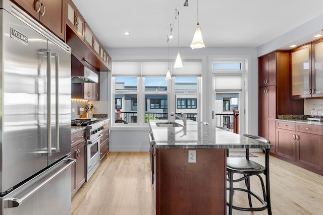 48 Federal St Unit B, Portland, ME 04101 - kitchen with high quality appliances, an island with sink, light wood-style flooring, glass insert cabinets, and a breakfast bar area