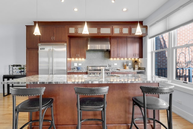48 Federal St Unit B, Portland, ME 04101 - kitchen featuring built in fridge, wall chimney range hood, glass insert cabinets, backsplash, and light wood-style flooring