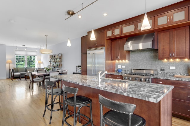 48 Federal St Unit B, Portland, ME 04101 - kitchen with stainless steel built in refrigerator, wall chimney range hood, a sink, light wood-type flooring, and decorative backsplash