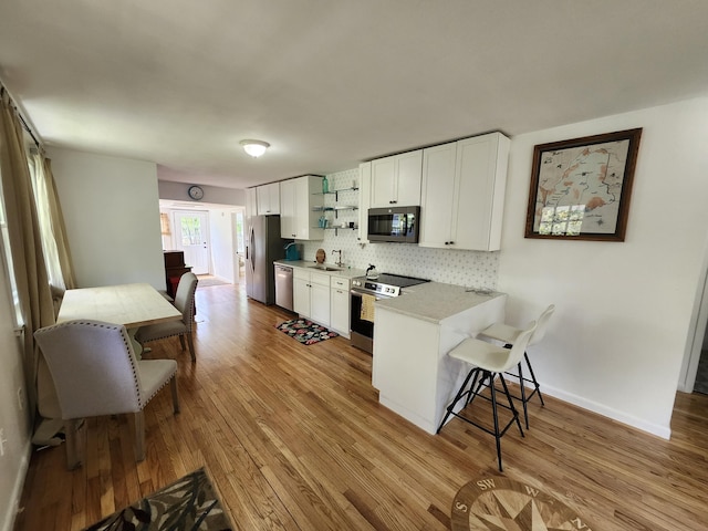 567 Ossipee Trl W, Standish, ME 04084 - kitchen with stainless steel appliances, a sink, a kitchen bar, white cabinets, and tasteful backsplash