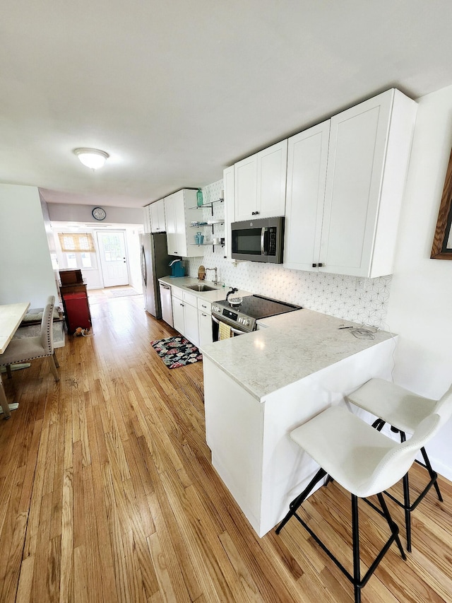 567 Ossipee Trl W, Standish, ME 04084 - kitchen with stainless steel appliances, a sink, light wood-style flooring, backsplash, and open shelves