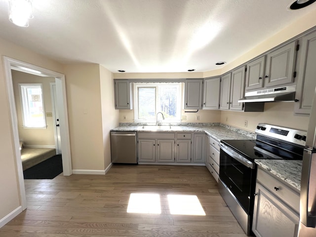 162 Beach St Unit 3, Saco, ME 04072 - kitchen with stainless steel appliances, under cabinet range hood, gray cabinetry, a sink, and light wood-type flooring