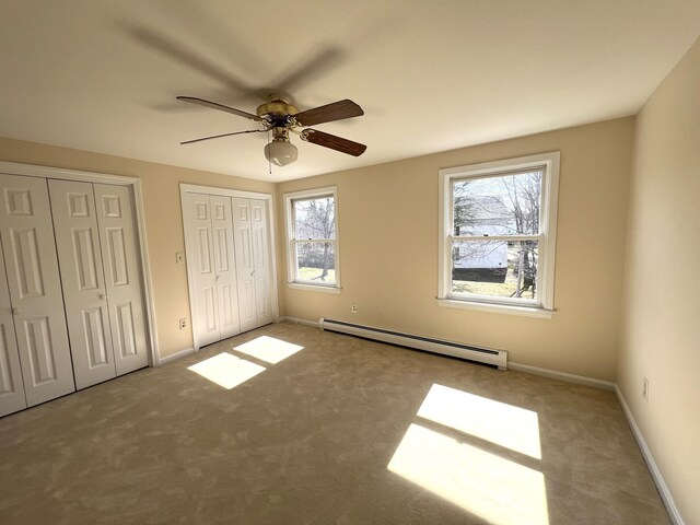 162 Beach St Unit 3, Saco, ME 04072 - unfurnished bedroom featuring baseboard heating, two closets, carpet floors, baseboards, and ceiling fan