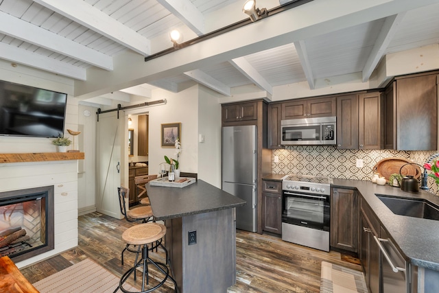 13 Ledge Rd Unit 3, Ogunquit, ME 03907 - kitchen featuring stainless steel appliances, a barn door, a sink, dark countertops, and beam ceiling