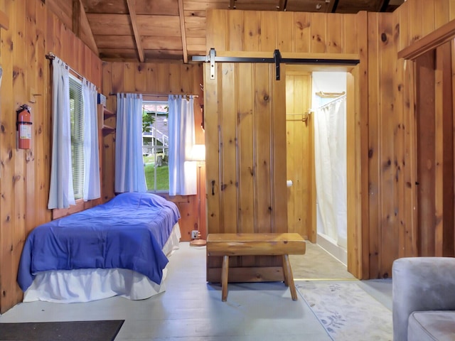 103 Taylor Woods Rd, Belgrade, ME 04917 - bedroom with wooden walls, a wood ceiling with exposed beams, and a barn door