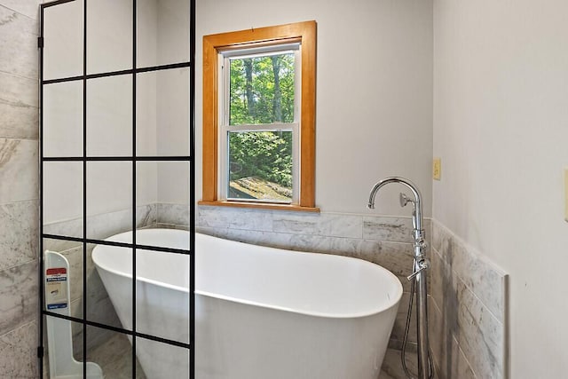 103 Taylor Woods Rd, Belgrade, ME 04917 - bathroom featuring tile walls, a soaking tub, and a wainscoted wall