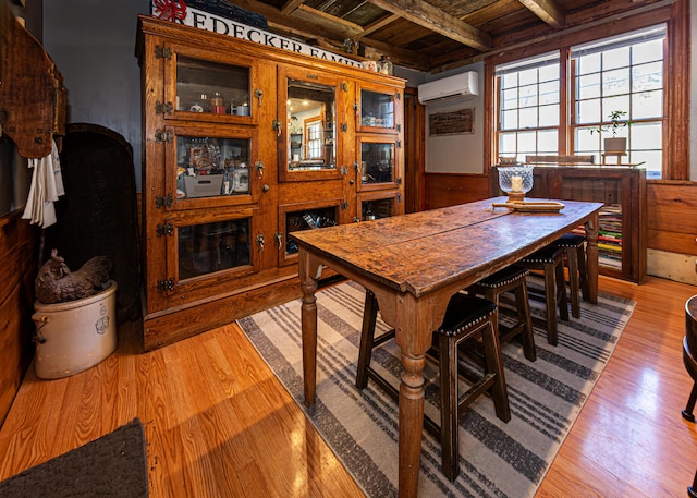 2103 US Highway 1, Sullivan, ME 04664 - dining space with an AC wall unit, wooden ceiling with exposed beams, light wood-style floors, wood walls, and wainscoting