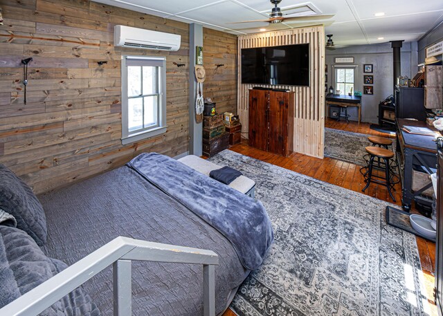 2103 US Highway 1, Sullivan, ME 04664 - bedroom featuring a wall mounted air conditioner, wood walls, wood-type flooring, and a wood stove