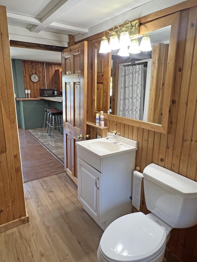 861 W Shore Rd, Otis, ME 04605 - bathroom with wooden walls, vanity, wood finished floors, toilet, and beam ceiling