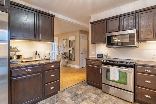 231 Parkway S, Brewer, ME 04412 - kitchen featuring stainless steel appliances, tasteful backsplash, dark stone counters, dark brown cabinetry, and light stone finish flooring