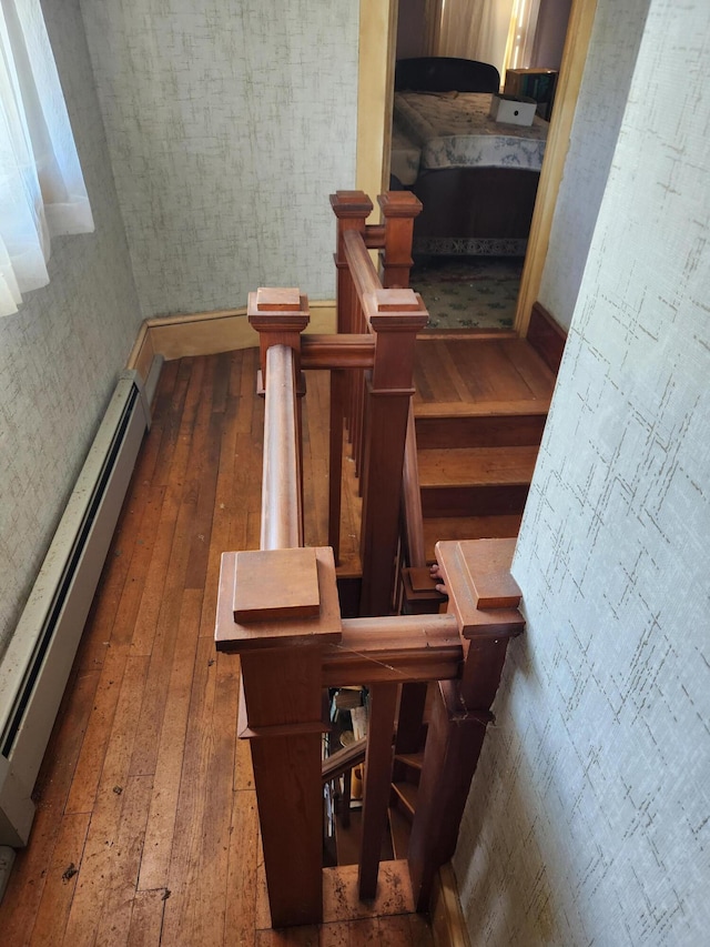 1542 Moosehead Trail Highway, Plymouth, ME 04969 - staircase featuring a baseboard radiator, wood-type flooring, wallpapered walls, and baseboards