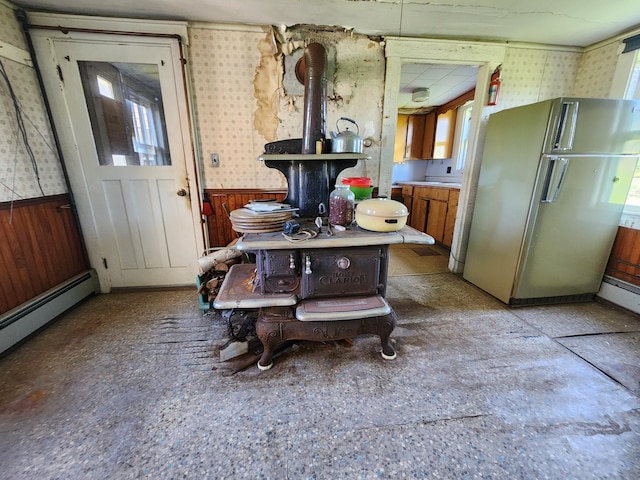 1542 Moosehead Trail Highway, Plymouth, ME 04969 - kitchen with a wood stove, freestanding refrigerator, wallpapered walls, wainscoting, and baseboard heating