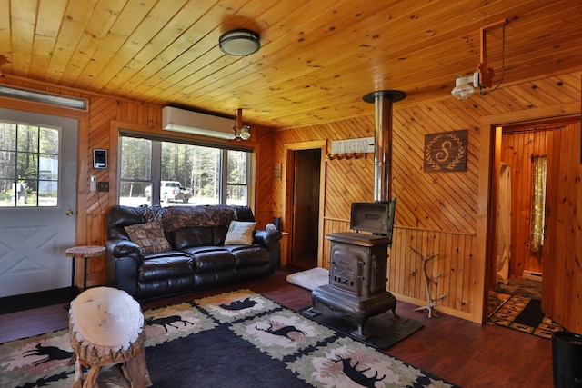 50 Hook Ln, Frenchtown Twp, ME 04441 - living area featuring a wood stove, wood finished floors, a wall mounted AC, wood walls, and baseboards