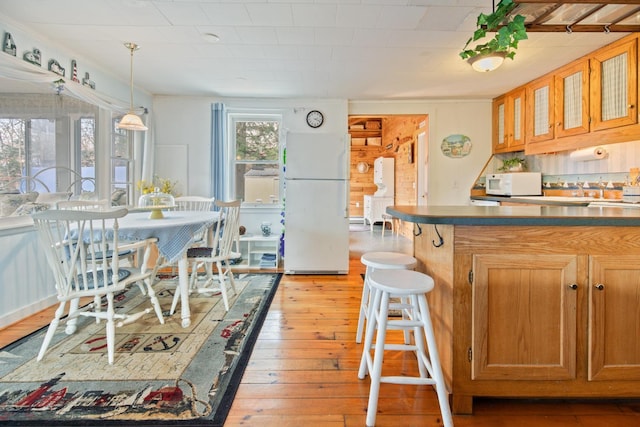 18 Scenic View Dr, Naples, ME 04055 - kitchen featuring white appliances, light wood finished floors, brown cabinets, glass insert cabinets, and pendant lighting