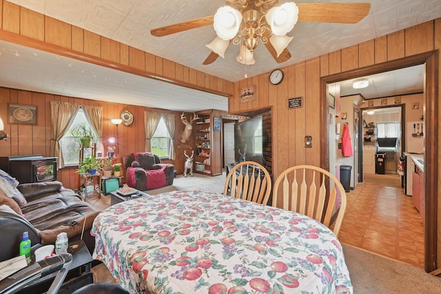 383 Main St, Pittsfield, ME 04967 - dining space with wood walls, a ceiling fan, and light carpet