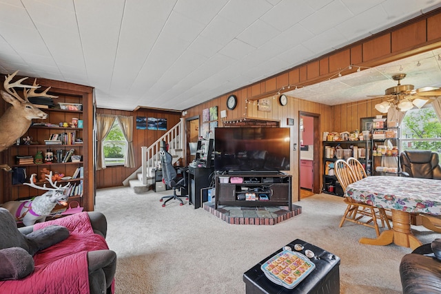 383 Main St, Pittsfield, ME 04967 - carpeted living room featuring healthy amount of natural light, wood walls, stairway, and ceiling fan
