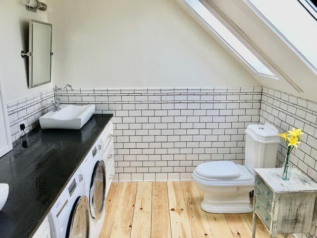 1 Forest St, Dover-Foxcroft, ME 04426 - bathroom featuring a skylight, tile walls, toilet, vanity, and wood finished floors