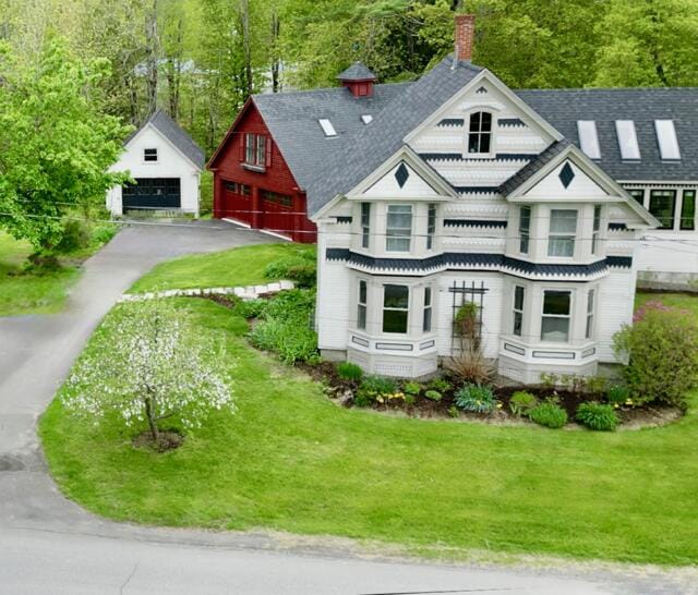 1 Forest St, Dover-Foxcroft, ME 04426 - victorian house featuring a garage, a chimney, an outdoor structure, a front yard, and a shingled roof