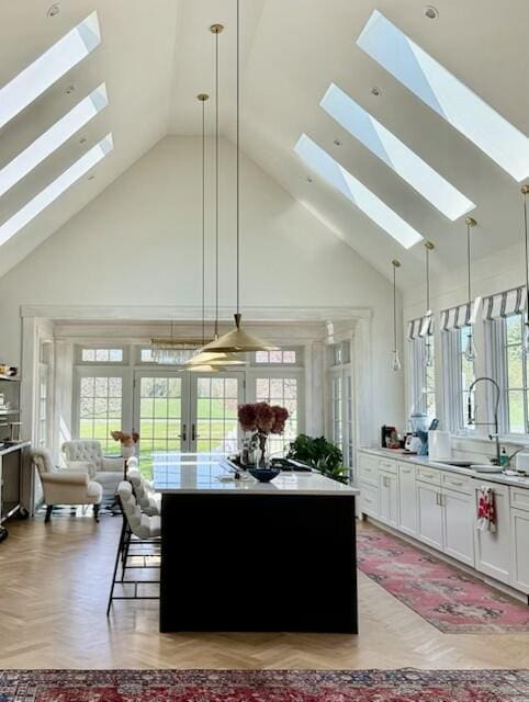 1 Forest St, Dover-Foxcroft, ME 04426 - kitchen with a skylight, high vaulted ceiling, a sink, open floor plan, and white cabinets