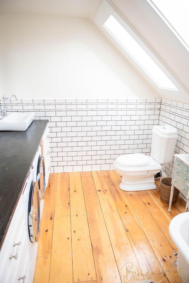 1 Forest St, Dover-Foxcroft, ME 04426 - bathroom with tile walls, vanity, vaulted ceiling, a wainscoted wall, and wood finished floors