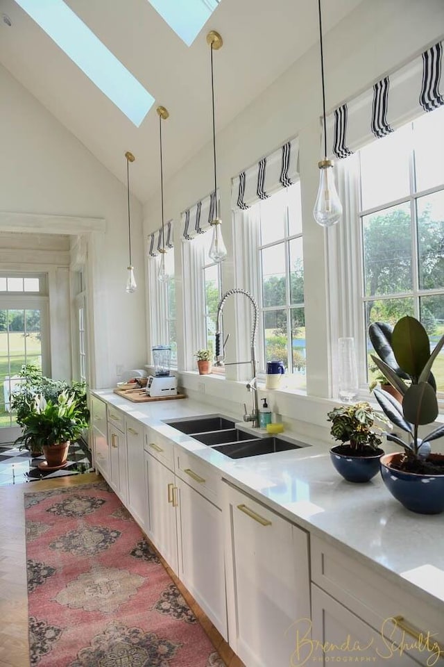 1 Forest St, Dover-Foxcroft, ME 04426 - kitchen featuring a skylight, light countertops, lofted ceiling, pendant lighting, and white cabinets