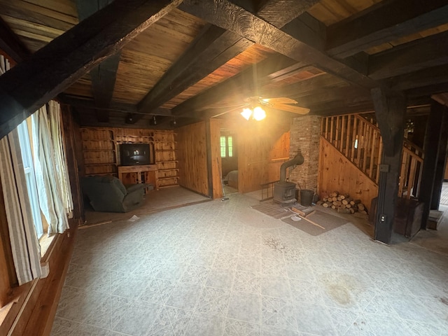 15 Sawyer Ln, Sanford, ME 04083 - unfurnished living room with a wood stove, stairs, wood walls, a ceiling fan, and wood ceiling with exposed beams