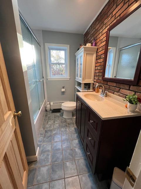 186 Clark Rd, Albion, ME 04910 - bathroom featuring toilet, a baseboard heating unit, vanity, baseboards, and shower / bath combination with glass door