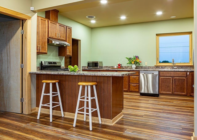 55 Diamond Point Rd, Lubec, ME 04652 - kitchen with appliances with stainless steel finishes, under cabinet range hood, dark wood-style flooring, a peninsula, and a kitchen bar