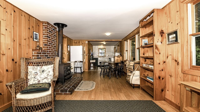 369 Narrow Gauge Trl, Hiram, ME 04041 - living room featuring a wood stove, wood walls, and light wood-style floors