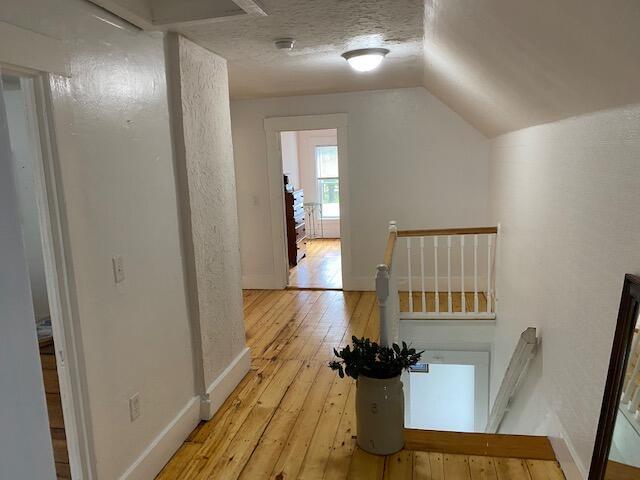 58 Main St, Sangerville, ME 04479 - hallway with an upstairs landing, light wood-type flooring, vaulted ceiling, and baseboards