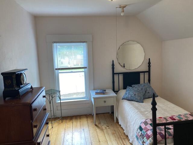 58 Main St, Sangerville, ME 04479 - bedroom featuring light wood-type flooring, a wood stove, and vaulted ceiling