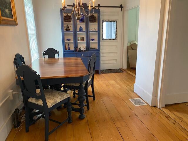 58 Main St, Sangerville, ME 04479 - dining space featuring a chandelier, light wood-style flooring, and a barn door
