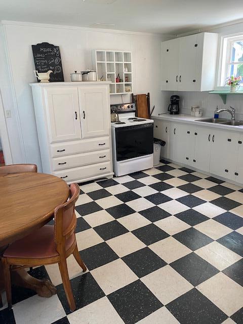 58 Main St, Sangerville, ME 04479 - kitchen with white range with electric stovetop, a sink, light floors, and white cabinets
