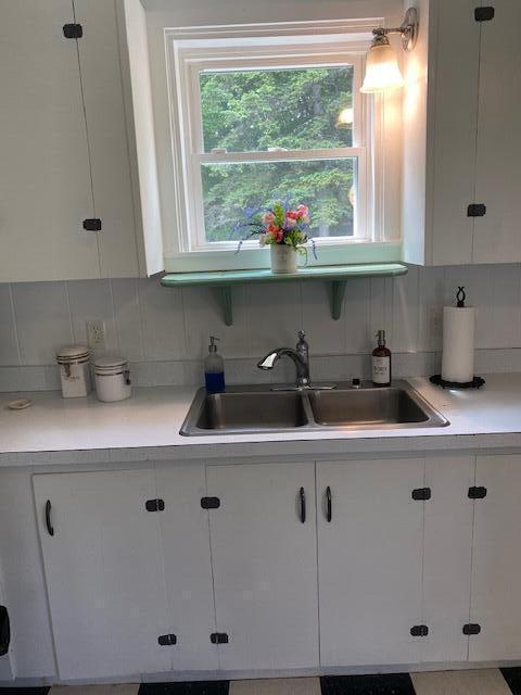 58 Main St, Sangerville, ME 04479 - kitchen with a sink, white cabinets, and decorative backsplash