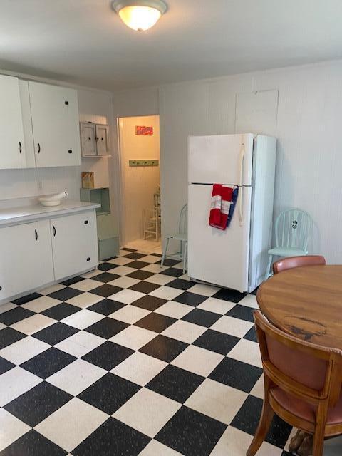 58 Main St, Sangerville, ME 04479 - kitchen featuring freestanding refrigerator, light countertops, light flooring, and white cabinetry
