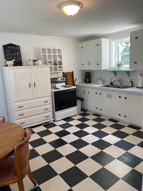 58 Main St, Sangerville, ME 04479 - kitchen featuring white electric range, a sink, light countertops, and decorative backsplash