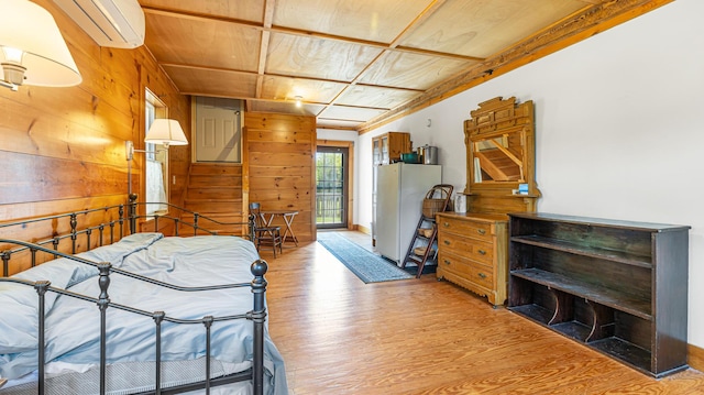 34 Mcphetres Rd, Sangerville, ME 04479 - bedroom with a wall mounted AC, wood finished floors, wood walls, and freestanding refrigerator