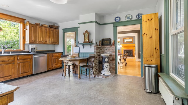 34 Mcphetres Rd, Sangerville, ME 04479 - kitchen featuring stainless steel dishwasher, brown cabinetry, plenty of natural light, and a brick fireplace