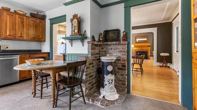 34 Mcphetres Rd, Sangerville, ME 04479 - kitchen with stainless steel dishwasher, baseboard heating, crown molding, a brick fireplace, and brown cabinetry