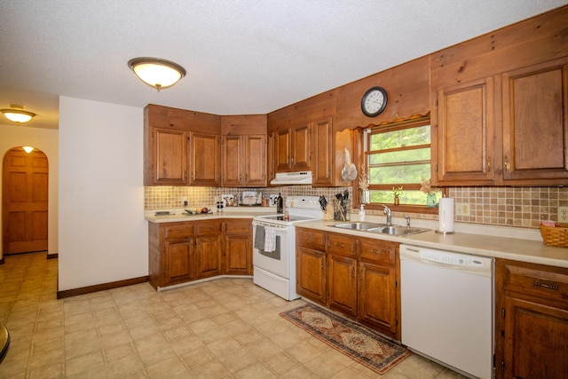 189 Stetson Rd E, Levant, ME 04456 - kitchen featuring white appliances, under cabinet range hood, brown cabinets, arched walkways, and a sink