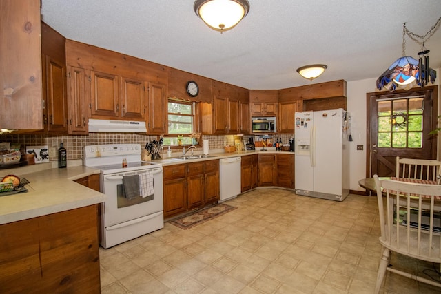 189 Stetson Rd E, Levant, ME 04456 - kitchen with white appliances, under cabinet range hood, a sink, light countertops, and brown cabinetry