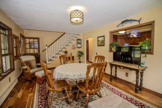 189 Stetson Rd E, Levant, ME 04456 - dining space featuring baseboard heating, arched walkways, stairway, and wood finished floors